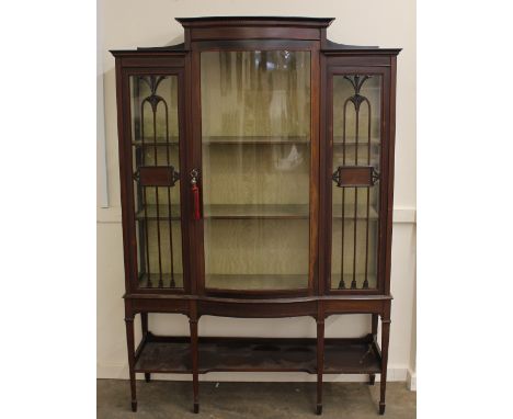 An Edwardian inlaid mahogany display cabinet, the fabric lined shelves enclosed by a bow fronted central door, raised on squa