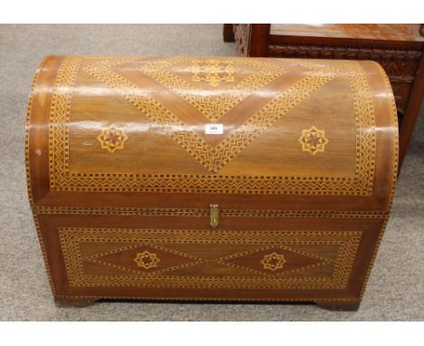An Eastern inlaid domed top trunk, decorated with stylised motifs and flanked by gilt metal carrying handles, 80cm wide