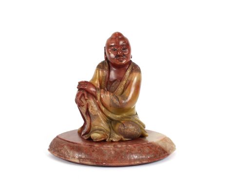 A Chinese carved hardstone figure of a seated man, with finely etched floral decoration to his cloak, on separate wood base, 