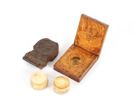 A carved wooden watch holder, in the Black Forest manner, AF; an inlaid and painted compass case; and two small decorated ivo