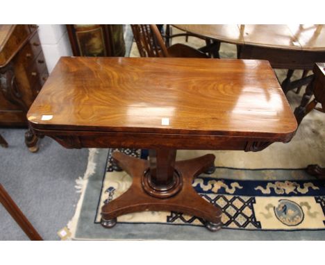 A 19th century mahogany foldover card table on an octagonal column with platform base and bun feet.