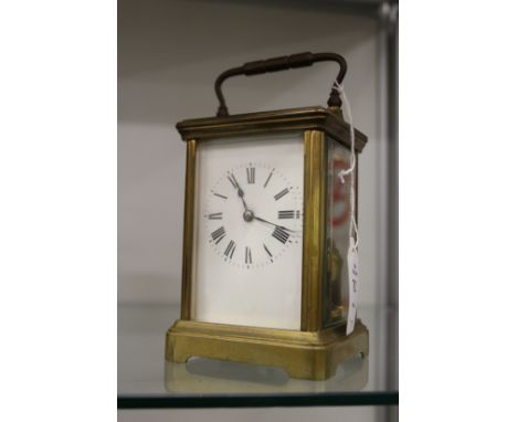 A brass carriage clock striking on a gong.