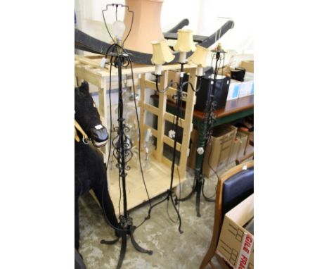 A pair of wrought iron standard lamps and a similar lamp.