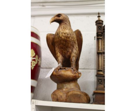 A carved wood model of an eagle on a rock.
