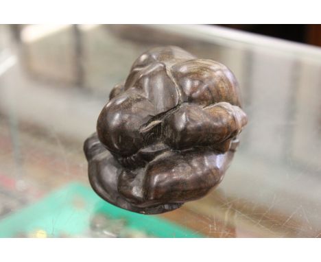 A carved wood model of a crouching man.