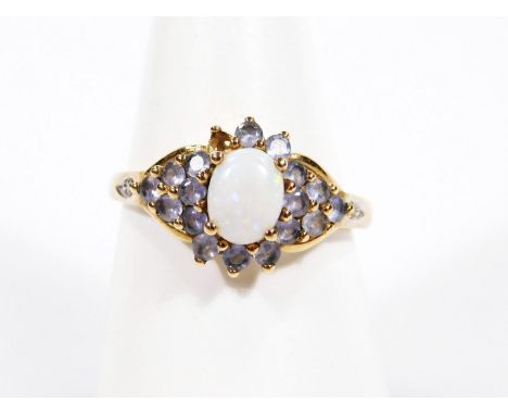 A ladies dress ring, claw set with a central opal surrounded by smaller pieces in a floral setting, on a part pierced shank m