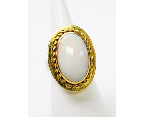 A large opal dress ring, with central opal in rub over setting, approx 6cm high, with reeded design borders, yellow metal, ma