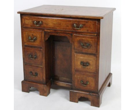 A 18thC walnut kneehole desk, of good proportion, the overhanging carved and shaped crossbanded top raised above a frieze dra
