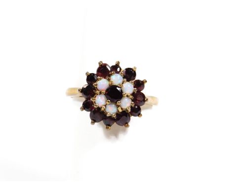 An early 20thC ladies garnet and opal dress ring, florally set on a part pierced shank marked 9ct, size M, 4g all in.