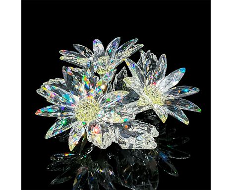 Three clear crystal flowers on a crystal base, the centers of each flower filled with small light yellow crystals. Swarovski 