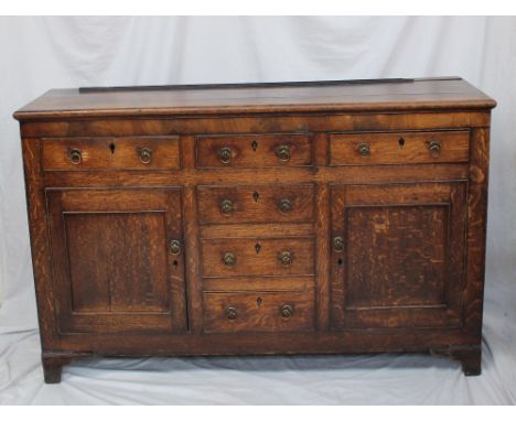 An 18th century North Wales oak dresser base, the planked top above a mahogany frieze and an arrangement of six drawers and t