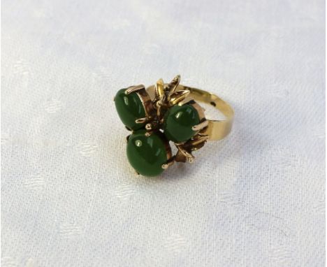 A Jade and yellow metal dress ring set with three oval jade panels to a yellow metal setting and shank