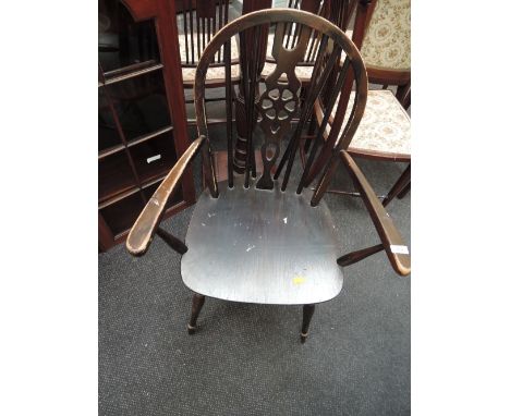 A traditional dark stained wheelback carver chair in the Ercol style