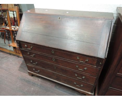 An early 19th century dark oak bureau having fitted interior with fret and shell decoration, with slope front and drawer base