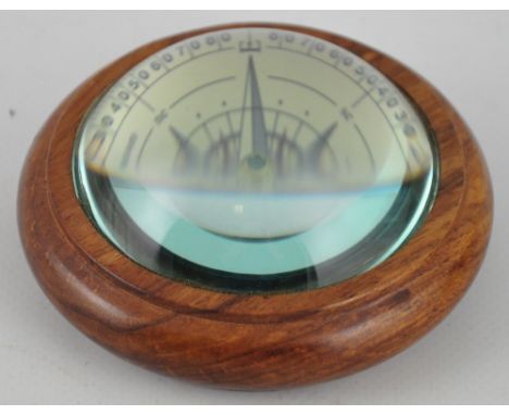 A wooden paperweight with magnified floating compass