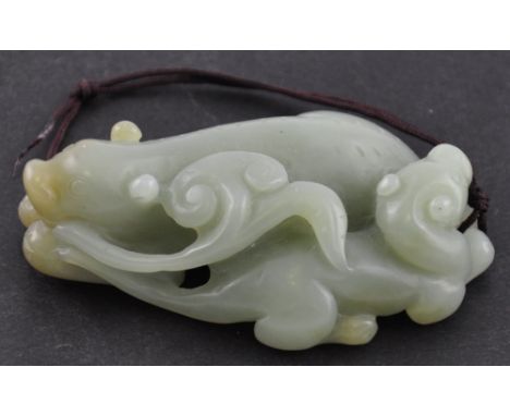 A Chinese jade pendant carved in the form of two beasts