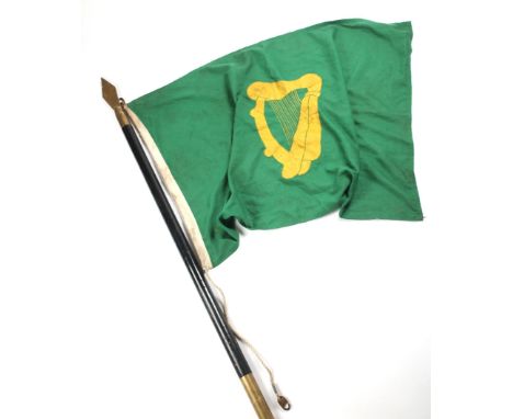 A green parade flag centred with a gold harp, on two-piece, ebonised pole, surmounted with a brass spearhead, flag 28" x 44" 