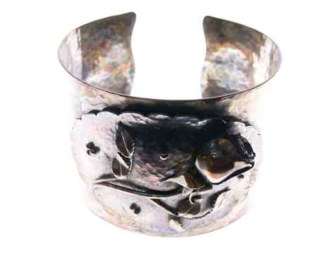 Unmarked white metal bangle of planished design with floral panel