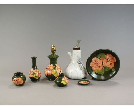 Seven pieces of Moorcroft in the Hibiscus design against a dark green ground, comprising a bottle vase, 16cm high, an ovoid v