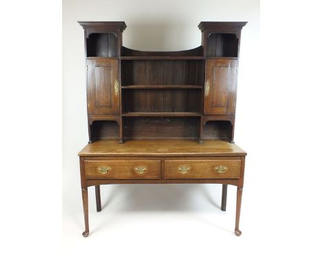 An oak dresser and rack with three open shelves and two cupboards to the rack and above two bevelled drawers with gilt brass 