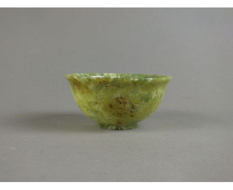 A Chinese serpentine bowl, 20th century, of mottled pale green hue with some light brown inclusions, of inverted bell form, 9