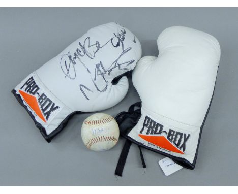 A pair of Pro-Box white leather boxing gloves, the left glove bearing the signatures of Nigel Benn, Steve Collins and Nicola 