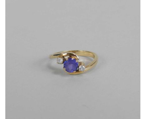 A tanzanite dress ring, designed as a central round mixed cut tanzanite flanked to each side by a faceted white stone, the ye