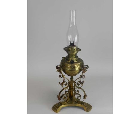 An Edwardian brass oil lamp, with embossed reservoir raised on scroll supports and a trefoil base, 40cm high (converted).