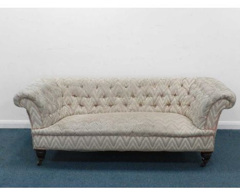 An upholstered Chesterfield sofa, of typical form with button back, raised on mahogany supports with ceramic castors, 210cm w