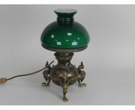 An Edwardian brass oil lamp, the globular reservoir raised on griffin feet, with green glass shade, 36cm high. (converted to 