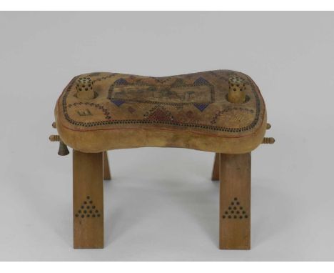 A vintage leather and wood camel saddle, Egyptian or Morrocan, with stitched and printed detailing. 65cm x 42cm x 43cm.