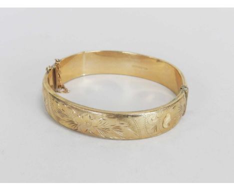 A 9ct gold hinged bangle, with bright cut engraved decoration and attached safety chain, weight approx 16.5gCondition report: