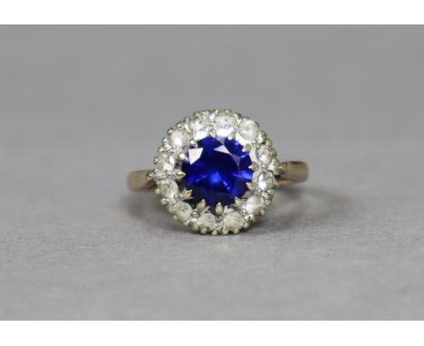 A 9ct gold ring set round-cut blue stone within a border of small white stones, size K, 3.4g.