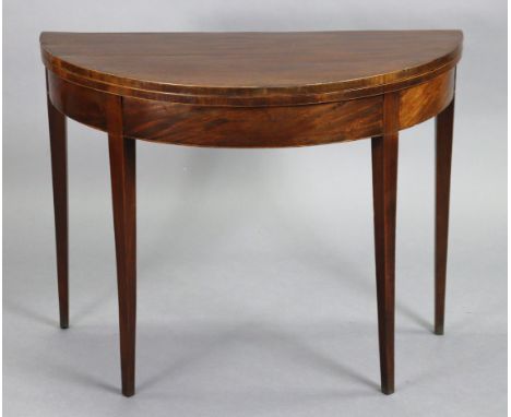 A mahogany demi-lune card table, the fold-over top lined with green baize , with plain frieze, on tapering square legs, 37¾” 