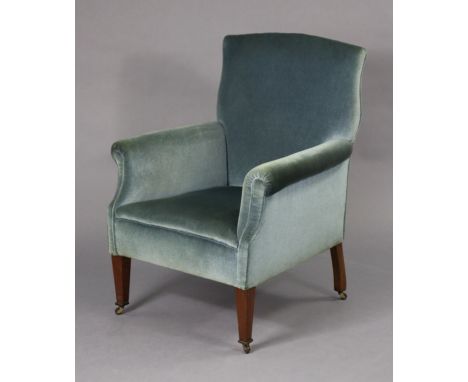 An Edwardian armchair with shaped square back, upholstered light blue velour, on square tapered mahogany legs with ceramic ca