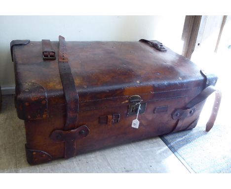 An early 20thC stitched brown hide cabin trunk with straight sides and a hinged lid, enclosing a removable tray interior, bea