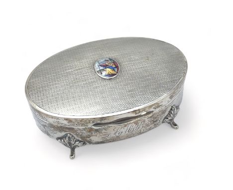 An oval silver hinged trinket box on four legs with engine turned patterned lid with a painted oval application, monogram to 