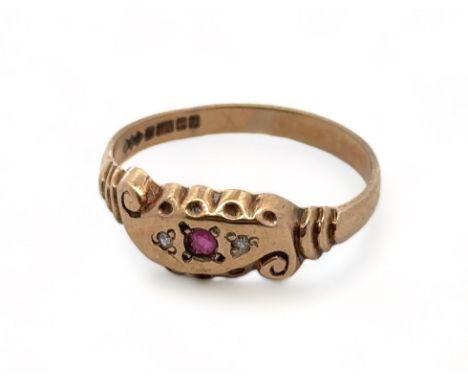 A 9ct yellow gold gypsy ring with scroll design and scalloped shoulders, set with two small diamonds and a central ruby. Size