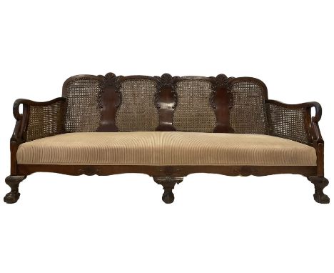 Early 20th century walnut bergere two seat sofa, the back and arms with double cane panels, the shaped back carved and applie