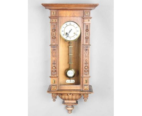 An early 20th century German oak cased Vienna style wall clock by Junghans, with eight day movement striking on a gong, the t