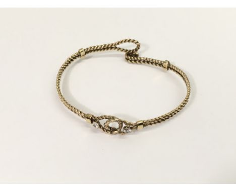An unmarked gold, twist bangle set with two white stones