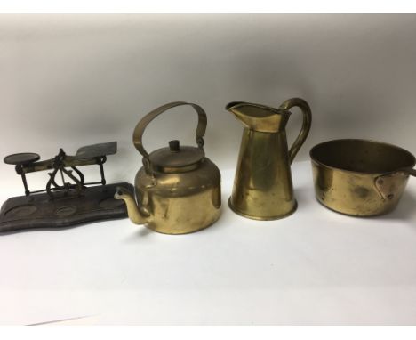 A group of brass items to include a Victorian saucepan, jug, swing handles kettle and a set of postal scales with no weights 