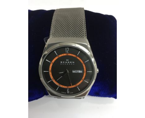 A gent's Skagen Titanium wristwatch with large, orange bezel face on woven steel strap