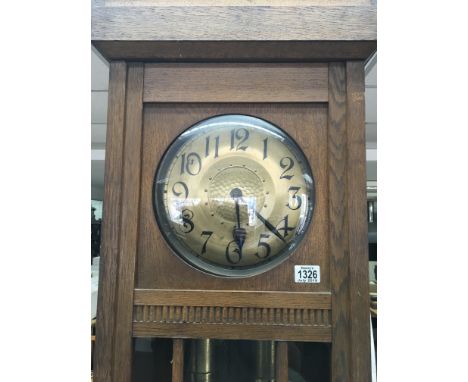 A 1920s oak longcase clock with a hammered finish brass dial and visible weights. Height 215cm