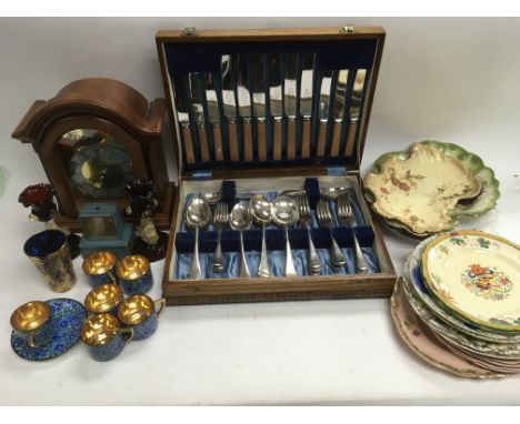 A box of odds comprising a cased cutlery set, various ceramic plates and glassware, mantle clock etc.