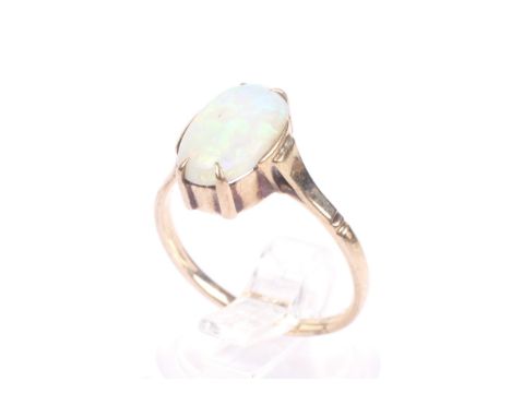 An early 20th century gold and opal single stone ring. The oval cabochon white opal displays a good, mainly green and yellow 