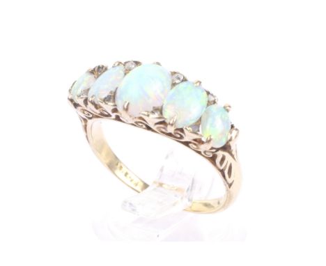 A late Victorian gold and opal five stone carved half-hoop ring with rose diamond points. The graduated oval cabochon white o