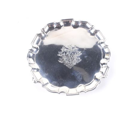 A George II silver shaped-round waiter. With a 'piecrust' moulded border on three feet and engraved at the centre with and sh