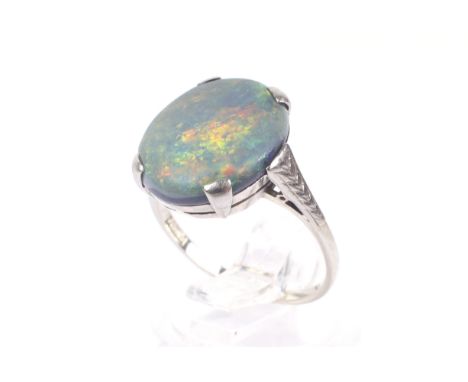 A mid 20th century white gold and black opal single stone ring. The oval cabochon black opal measures approx. 14.4mm x 12.0mm