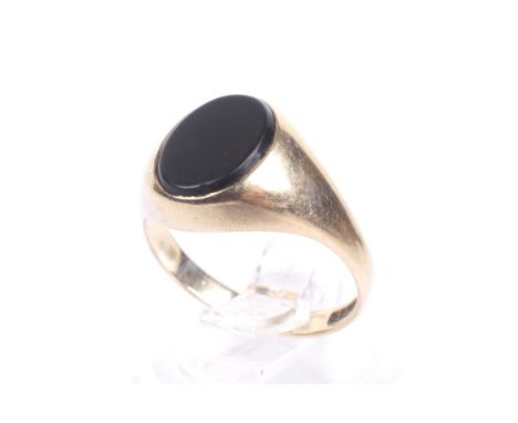A vintage 9ct gold and black onyx oval signet ring. The oval black onyx panel rub-over set between tapering shoulders on a sh
